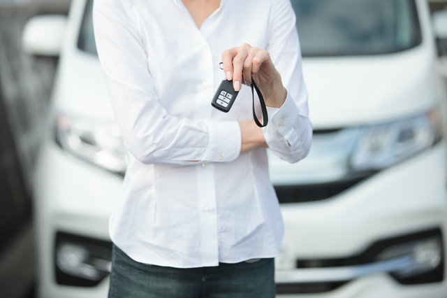 車のスマートキーを持つ女性